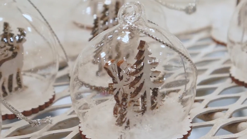 A Close-Up of A Handmade Snow Globe Ornament Featuring a Tree and Reindeer Inside