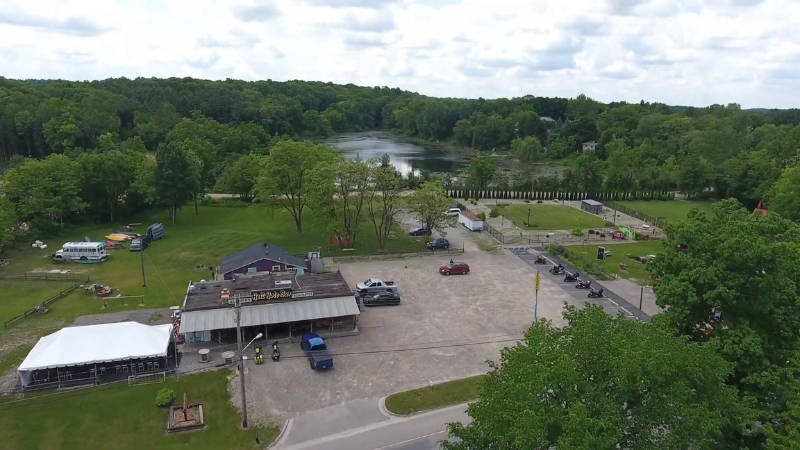 An aerial view of Hell Hole Bar & Diner in Michigan, surrounded by greenery and a nearby lake